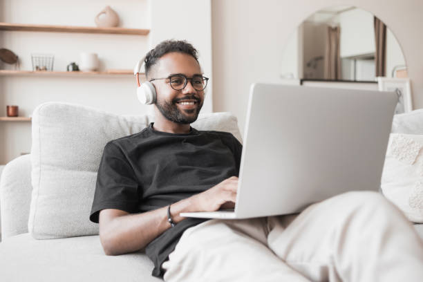 Handsome man using laptop working at home, online meeting, distance studying stock photo
