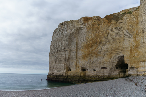 Rock formation on a cloudy summer day with tunnel as connection from the beach Plage d'Antifer to the next beach, Etretat, Normandy, France