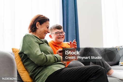 istock Little boy with down syndrome enjoy spending time with mother and watching mobile phone 1423036245