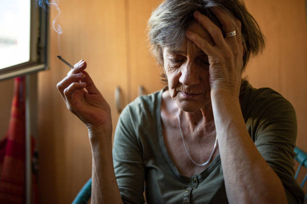 Woman in depression A woman is sitting in a very depressed mood, holding cigarette smokers wrinkles stock pictures, royalty-free photos & images