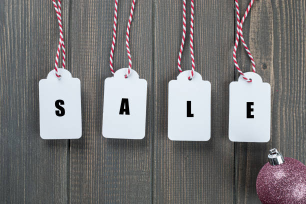Pink colored christmas bauble and hanging price tags with red and white ribbons written SALE on it.
