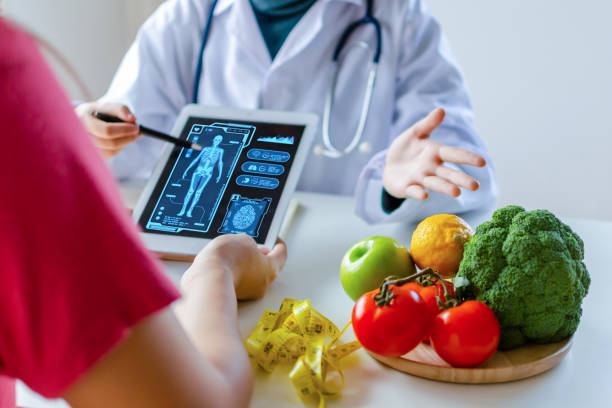 nutritionist female doctor using digital mobile tablet with virtual graphic icon diagram and vegetable and fruit with patient on desk at office hospital, nutrition, food science, healthy food concept nutricionista doctora usando tableta móvil digital con diagrama de icono gráfico virtual y verduras y frutas con el paciente en el escritorio en el hospital de la oficina, nutrición, ciencia de los alimentos, concepto de alimentos saludables