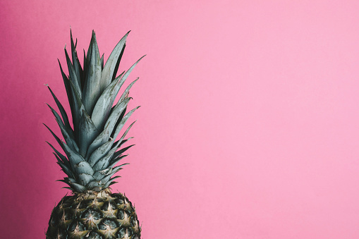 Part of single pineapple on pink background.