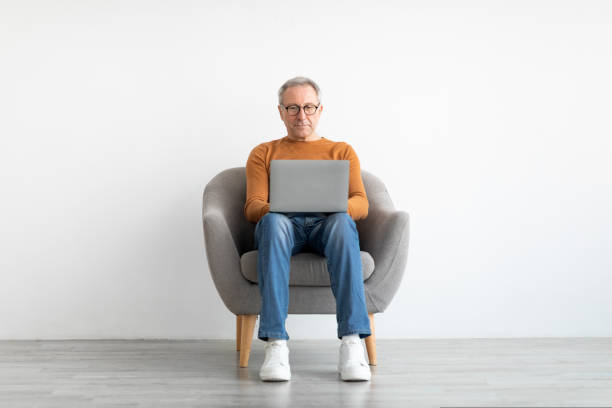 istock Confident mature man using laptop at home 1423040761
