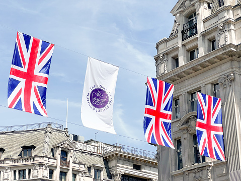 Oxford Circus in downtown London decorated with British flags and the official logo for the Platinum Jubilee of Queen Elizabeth II in May 2022. Sunny day.