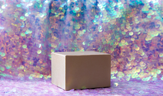 Beautiful iridescent purple color sequins textile background with square shape box pedestal for products. Lot of copy space. Side view.