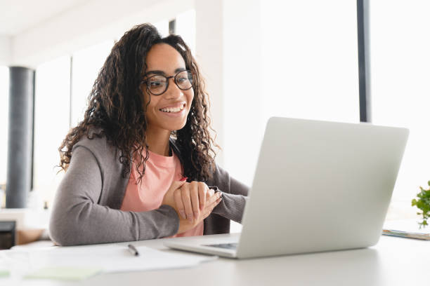 Happy young african student businesswoman freelancer watching video webinars online, having videocall conversation, e-learning, tutoring at home office stock photo