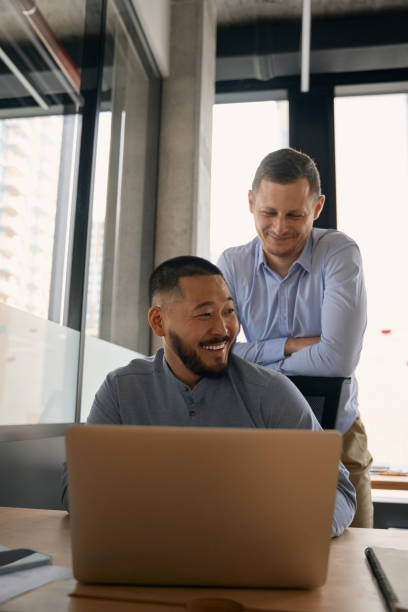 istock Joyful corporate worker and his pleased coworker in workplace 1423054627