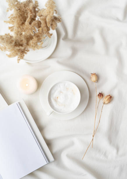 istock white blank book with cup of coffee and burning candle , cozy composition with opened book mockup 1423055274
