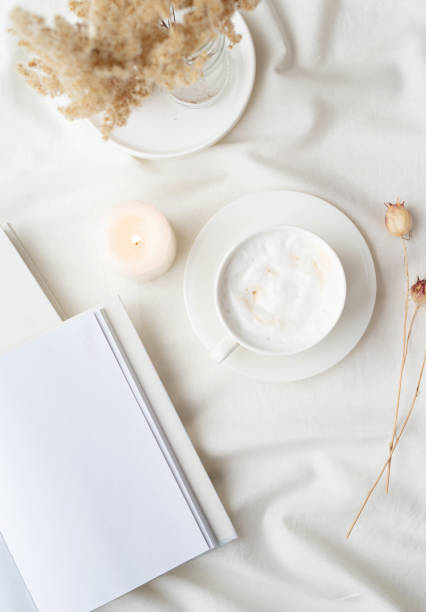 istock white blank book with cup of coffee and burning candle , cozy composition with opened book mockup 1423056360
