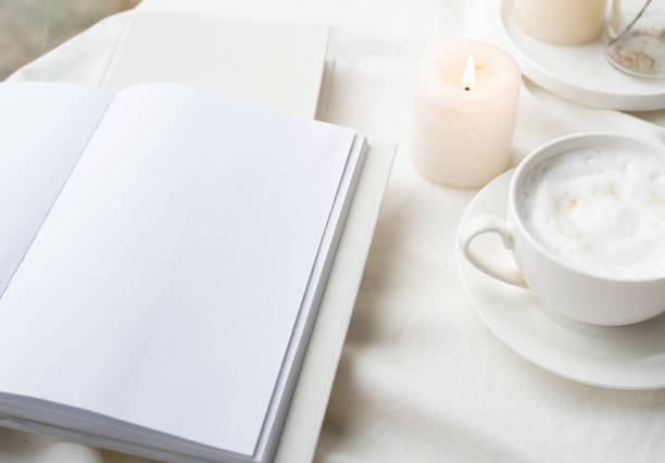 istock white blank book with cup of coffee and burning candle , cozy composition with opened book mockup 1423056505