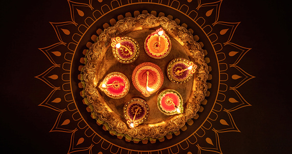 Deepavali Diwali, Hindu Festival of lights celebration. Diya oil lamp lit on traditional Puja thali, top view.