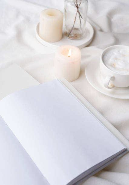 istock white blank book with cup of coffee and burning candle , cozy composition with opened book mockup 1423056732