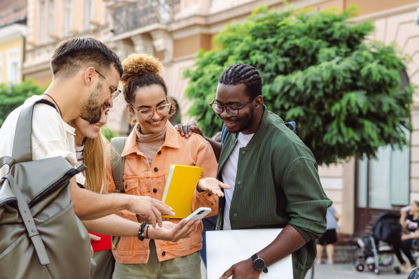 istock Cheerful students using smart phone on the street 1423061720
