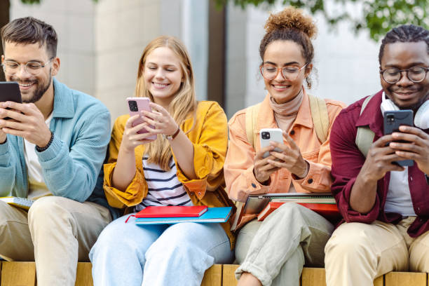istock Group of cheerful students sitting together and using their smart phones 1423063207