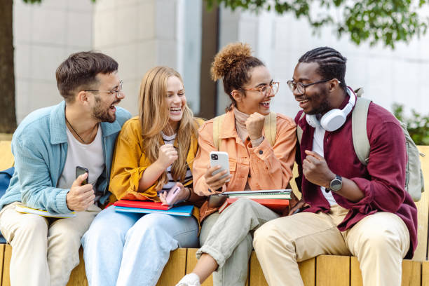 istock Group of cheerful students sitting together and using their smart phones 1423063378