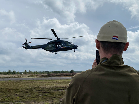 Leopoldsburg, Belgium, - September 10, 2022. Young man is watching a landing helicopter at the International Sanicole airshow airshow in the middle of a rain shower.