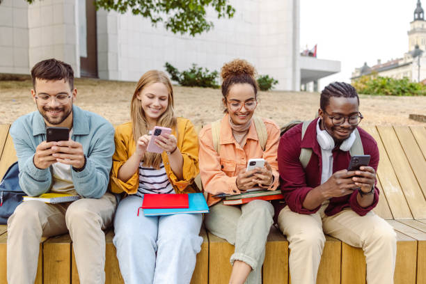 istock Group of cheerful students sitting together and using their smart phones 1423063771