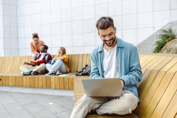 istock Male student using laptop on the bench on campus 1423063972
