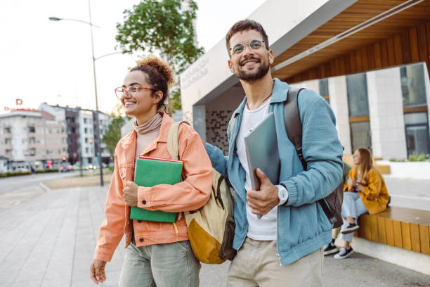 Students talking and waiting a bus on a station stock photo