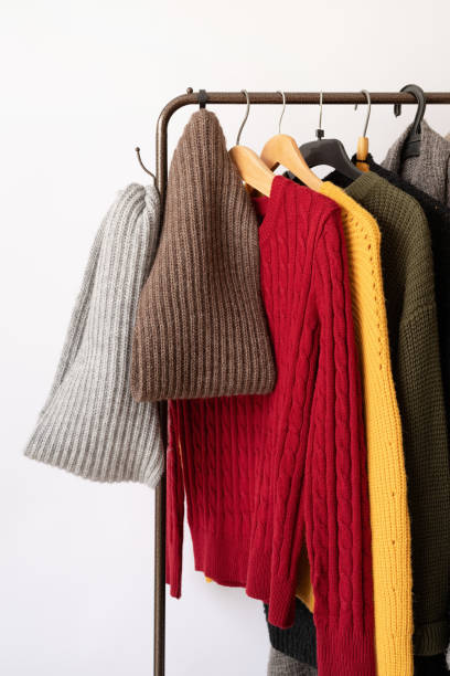 istock Row of different colorful Knitted sweaters hang on hangers, white background 1423065361