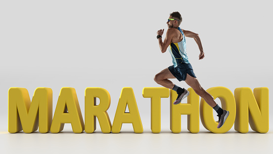 Energy and speed. Triathlon male athlete running along 3d lettering Marathon over white background. Concept of healthy lifestyle, sport, action, motion. Side view.