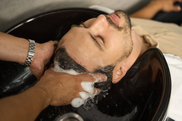 Male hairdresser drying hair of the female client at the beauty salon. Small business hair salon.
