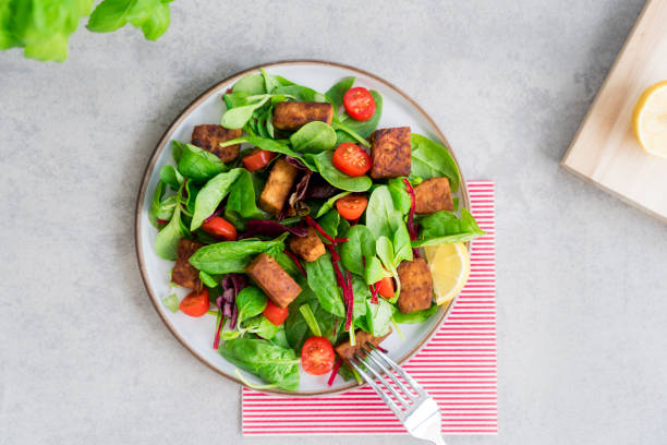 istock Top view healthy salad with roasted tempeh, cherry tomato, beetroot straws, spinash and lettuce leaves on plate. Tempeh is fermented soy bean. Plant based protein. Healthy Cooking and eating. Go vegan 1423074589