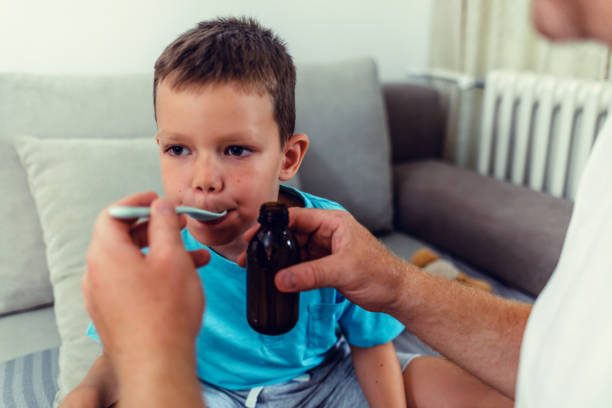istock Man pouring syrup for sick boy. 1423077330