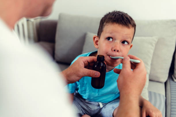 istock Man pouring syrup for sick boy. 1423077448
