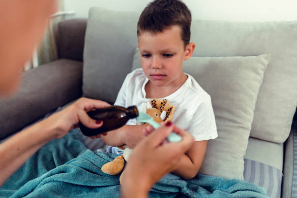 istock Mother giving son cough syrup at home. 1423077499