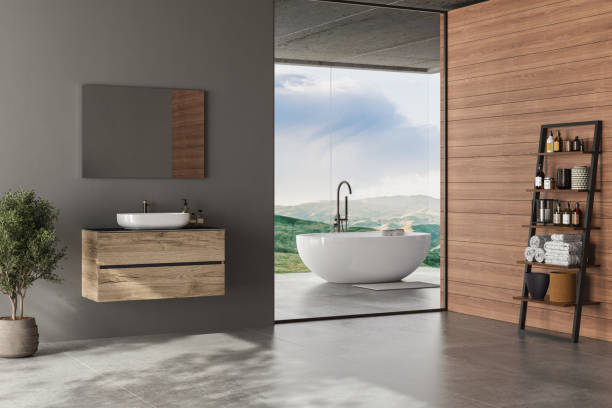 istock Modern gray bathroom interior with concrete floor, panoramic window with city view, dark wall, white bathtub, and sink with vertical mirror and wooden vanity. 3d rendering copy space 1423077570