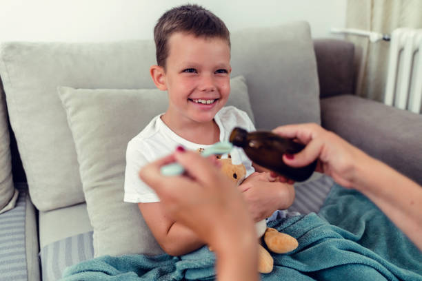 istock Mother giving son cough syrup at home. 1423077931