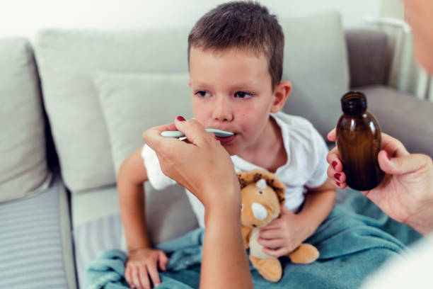 istock Mother giving son cough syrup at home. 1423078225