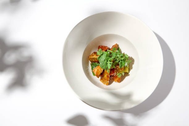 istock Crispy eggplant in chinese style on white plate. Crispy eggplant salad on summer menu. Asian appetizer - roasted aubergine with coriander leaves. Vegan food. Aesthetic veggie menu. 1423081033