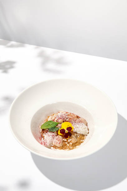 istock Creative creamy risotto with eel and cheese espuma. Fish risotto on white plate with unagi sauce and eel in summer menu Italian risotto from chef with smoked eel and spinach with shadows of leaves 1423081206