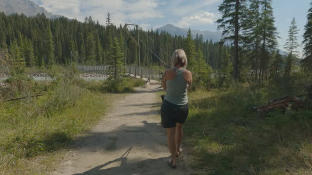 Dynamic shot of a woman walking a dog in the wilderness