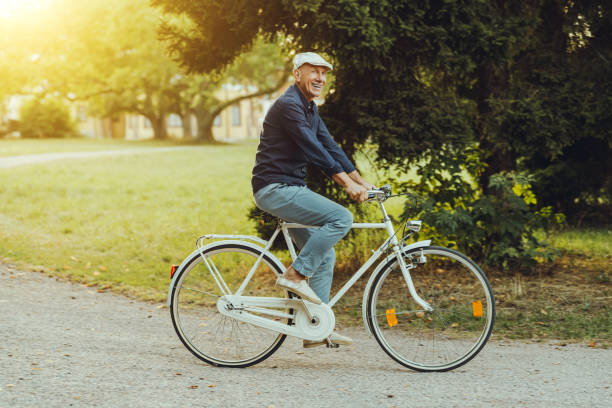 Senior Asian woman riding a vintage bicycle outdoors. Healthy lifestyle concept, active aging, leisure activity, casual fashion, enjoying freedom and independence in everyday life.
