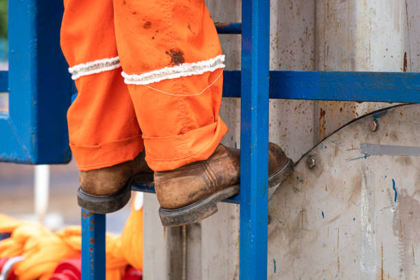 Action of a construction worker is climbing on the platform ladder. An industrial working with unsafe action scene photo, close-up at the safety shoe.