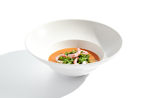 Summer Spanish soup gazpacho with shrimp and rocket salad isolated on white background. Healthy cold tomato soup with prawns. Clean eating for diet.Healthy food in restaurant menu. Seafood gazpacho