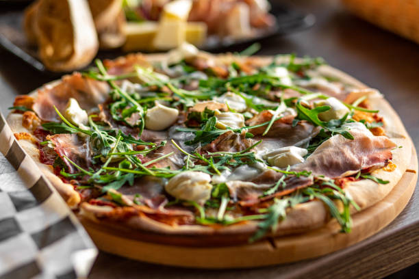 istock Pizza with greenery, mozzarella cheese, bacon, meat, tomato with spice on the cafe table. Pizzeria, Italian fast food 1423092269