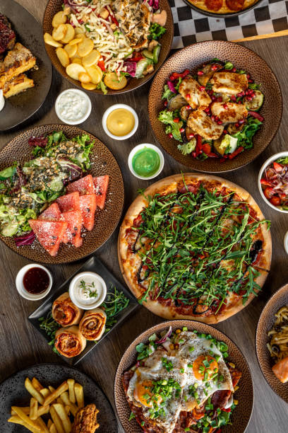 Vertical pizza, cinnamon or pepperoni puff pastry rolls with filling, seafood. Chicken, meat with sauce, potato and eggs Vertical pizza, cinnamon or pepperoni puff pastry rolls with filling, seafood salad. Chick, meat with sauce, fried sliced potato, grill salads, scrambled eggs with spice, carnitas. Flat lay, top view restaurant table layout stock pictures, royalty-free photos & images