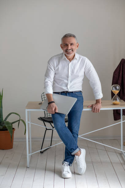 istock Gray-haired mid aged businessman with a laptop in hands 1423093641