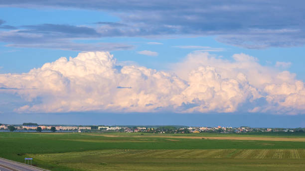 Clouds over the green field near the road Clouds over the green field near the road horizon over land stock pictures, royalty-free photos & images