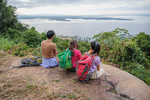 Small Group of young Asian people hikers with backpacks enjoying looking at on top of the mountain landscape valley lake view, Beauty in Nature and Horizon over water, Namphong National Park (Hin Chang Si), Khon Kaen, Thailand, Adventures and exploring concept