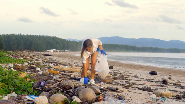 istock Volunteer woman picking up plastic bottle into trash bag from beach 1423102368