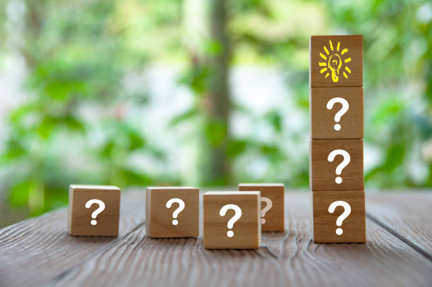istock Wooden cube block with light bulb surrounded by questions marks. Solution and idea concept 1423111532