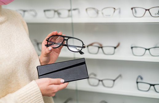 Modern stylish eyeglasses holding in hand. Fashionable optical eyewear accessory.