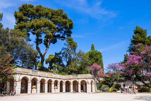 Tourists visiting the Colline du Château in Nice, where, strolling in in the numerous footpaths, you can find roman remains, fountains, shady lawns with benches and panoramic points