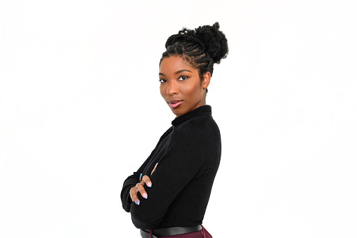 Portrait of lovely African American woman. Female model in black long sleeve shirt and trousers standing against white background, looking at camera. Portrait, beauty, studio photoshoot concept